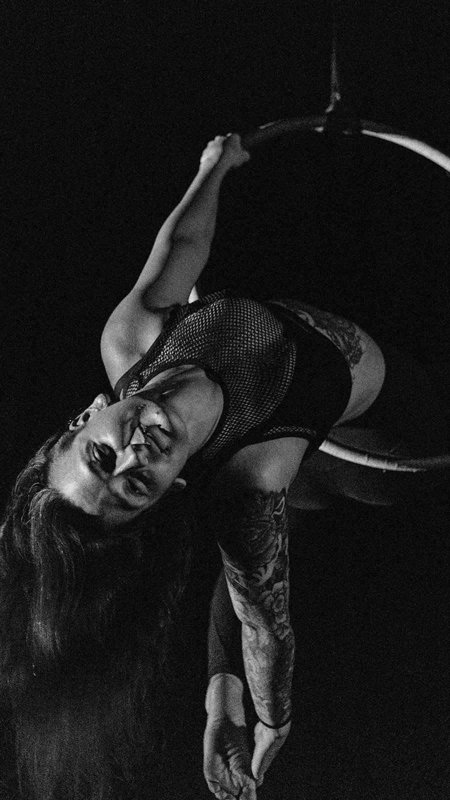 A stunning aerialist performing gracefully on a Lyra in an outdoor setting.