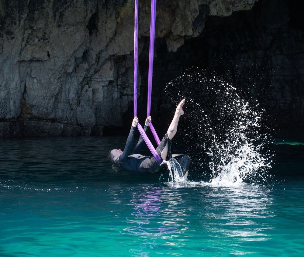 Petra Kalliommaa performing a technical sling movement against a coastal backdrop.